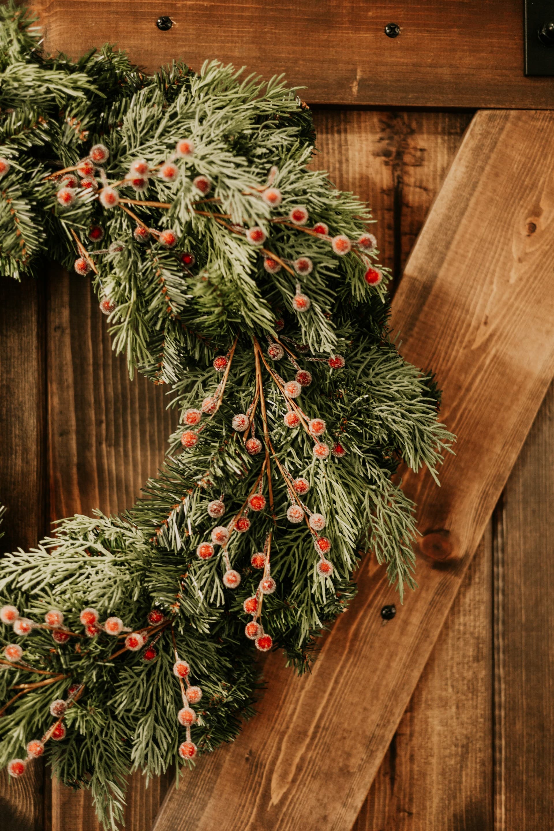 Christmas wreath with red berries and evergreen foliage on a wooden door