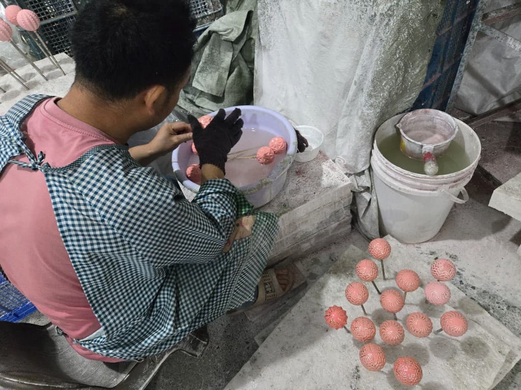 Factory worker hand-finishing embossed Christmas ornaments for OEM and ODM wreath accent programs
