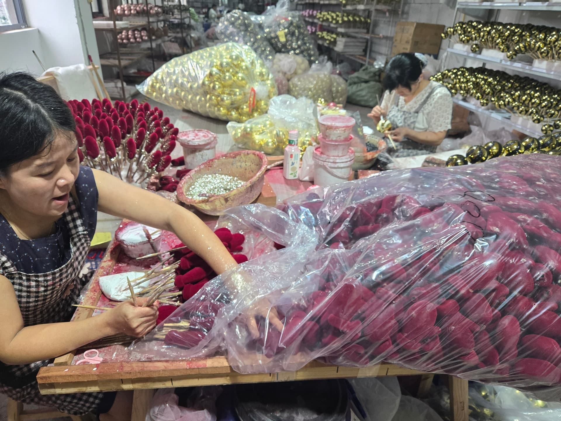 Hand-assembling Christmas ball ornaments on factory showcase craft stations